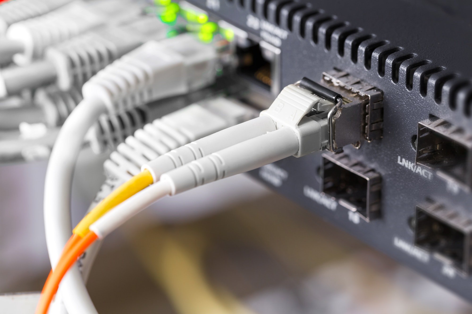 Total OTN Solutions – Nahaufnahme eines Hochgeschwindigkeits-Glasfasernetzwerk-Switches und von Kabeln im Rechenzentrum